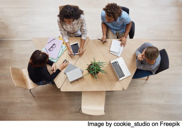 an overhead view of 4 people sitting at a table having an office meeting