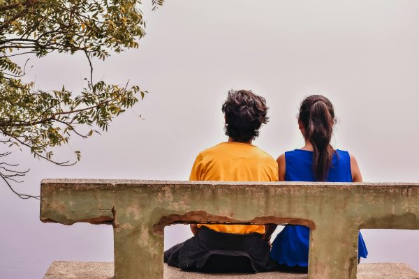 Two people sitting beside each other outside